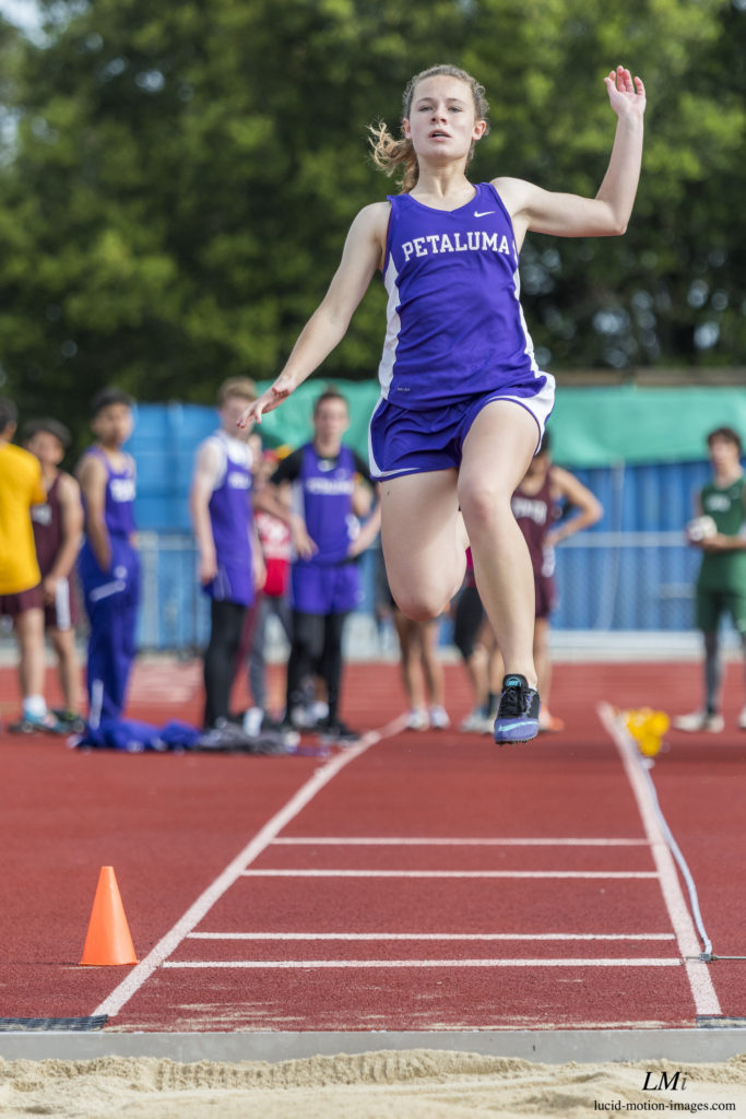 Athlete prepares for pole vault on a track with others watching.