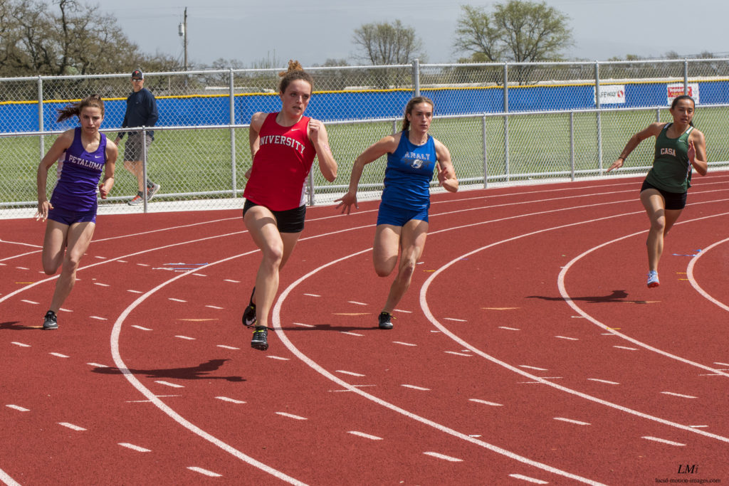 Athlete prepares for pole vault on a track with others watching.