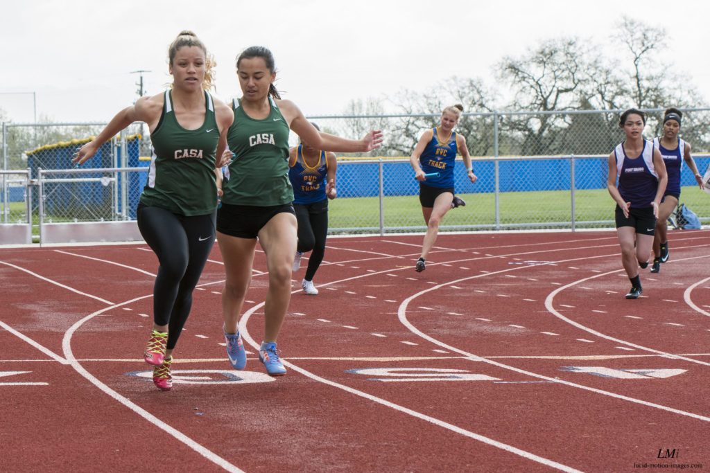 Athlete prepares for pole vault on a track with others watching.
