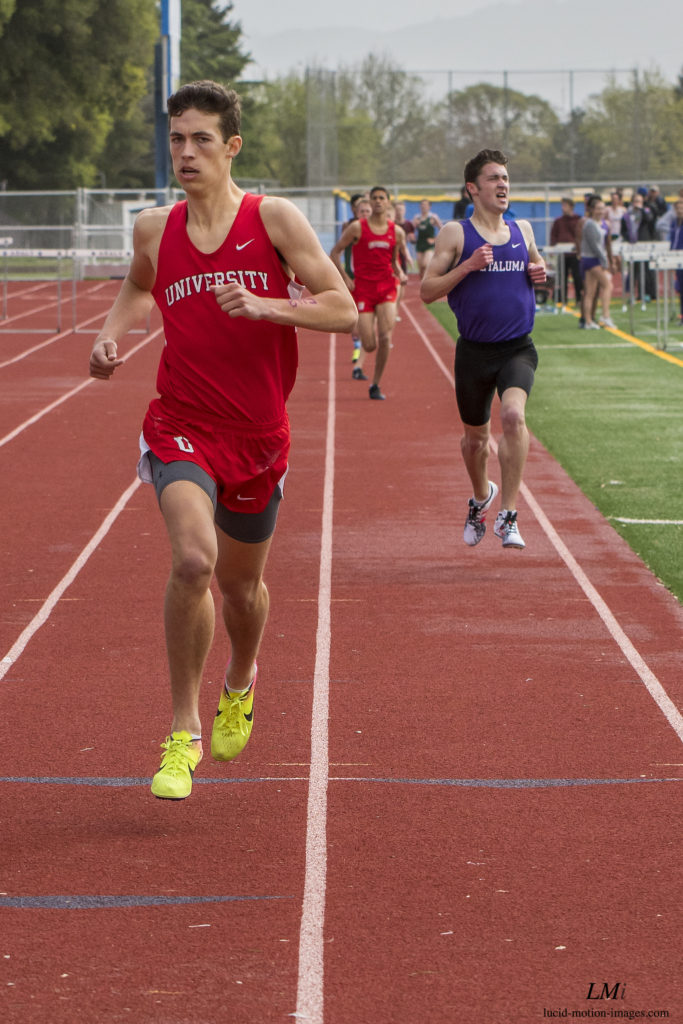 Athlete prepares for pole vault on a track with others watching.