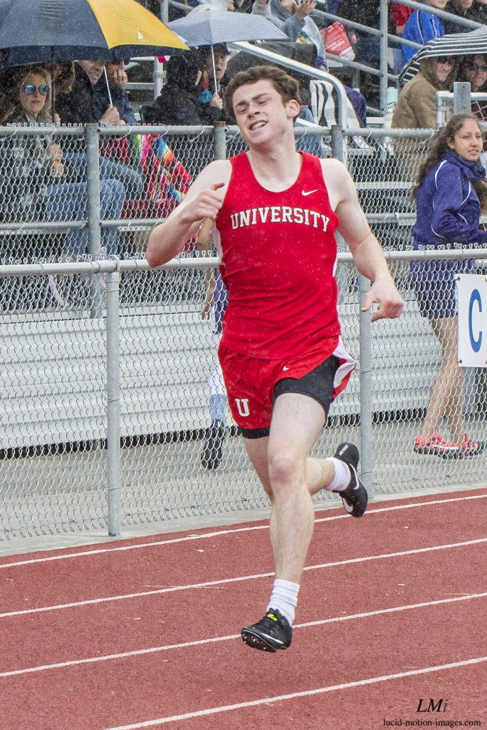 Athlete prepares for pole vault on a track with others watching.