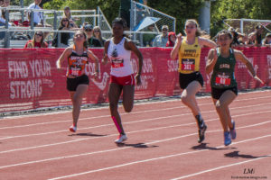 Athlete prepares for pole vault on a track with others watching.
