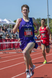 Athlete prepares for pole vault on a track with others watching.