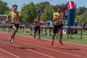 Athlete prepares for pole vault on a track with others watching.
