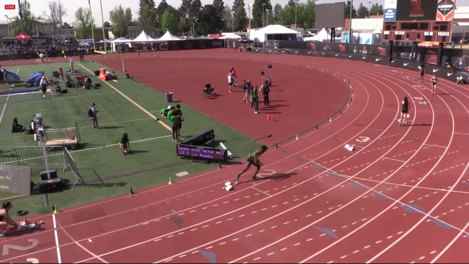 Athlete prepares for pole vault on a track with others watching.