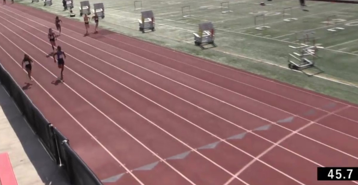 Athlete prepares for pole vault on a track with others watching.