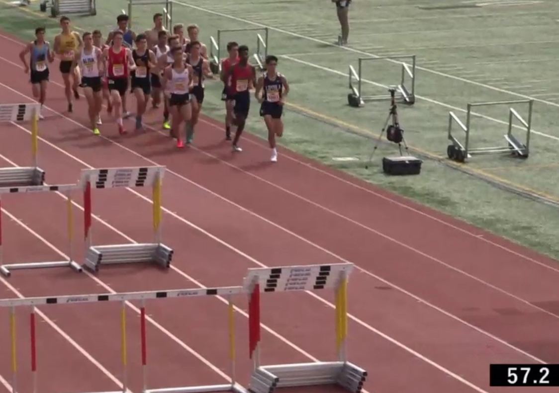 Athlete prepares for pole vault on a track with others watching.