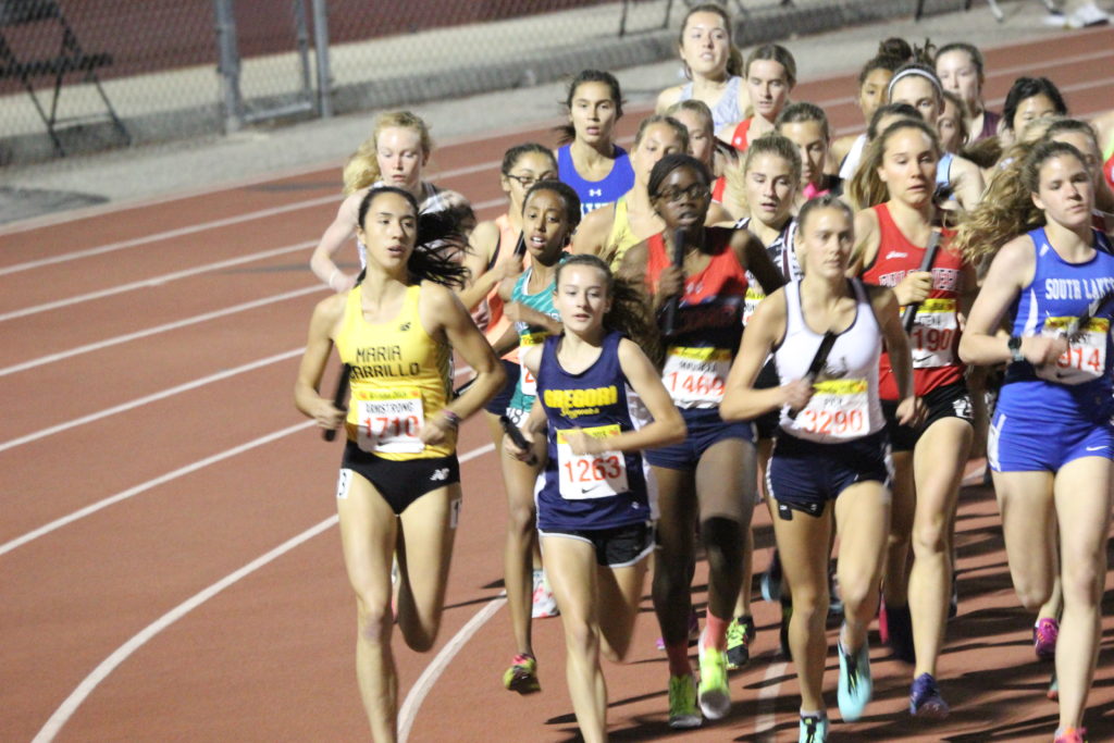 Athlete prepares for pole vault on a track with others watching.