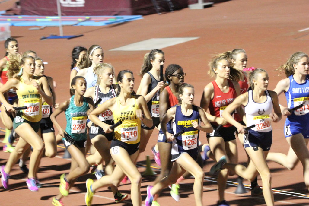 Athlete prepares for pole vault on a track with others watching.