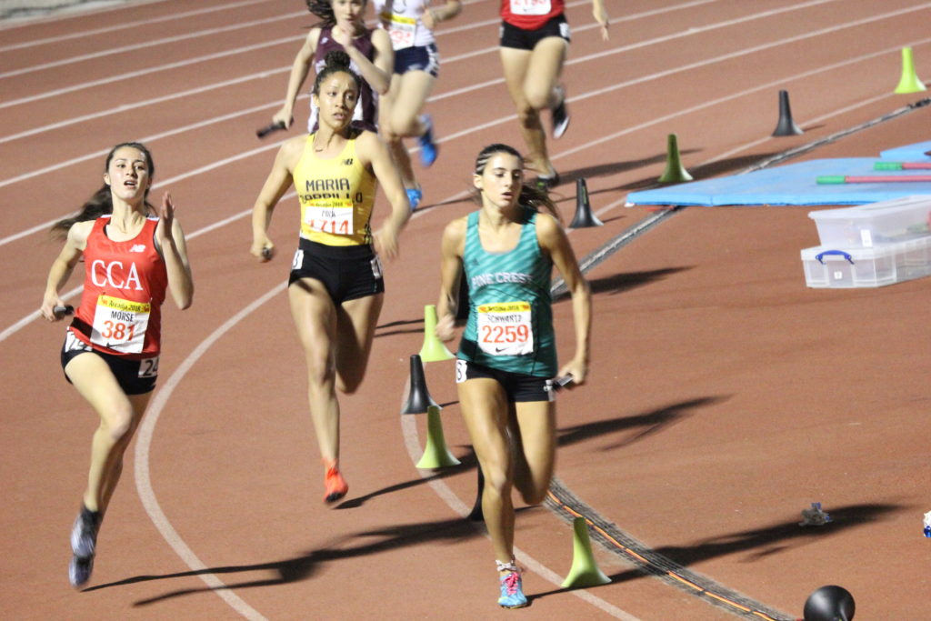 Athlete prepares for pole vault on a track with others watching.