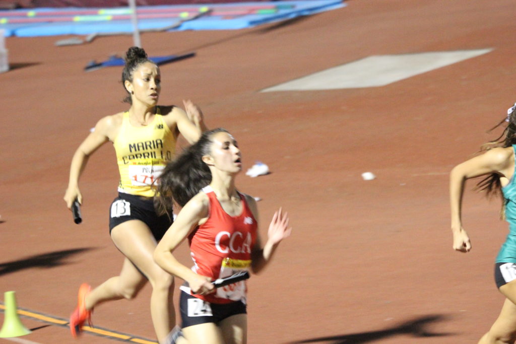 Athlete prepares for pole vault on a track with others watching.