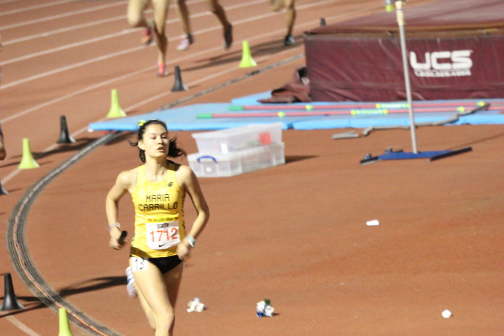 Athlete prepares for pole vault on a track with others watching.