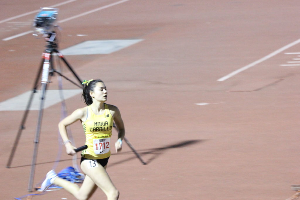 Athlete prepares for pole vault on a track with others watching.