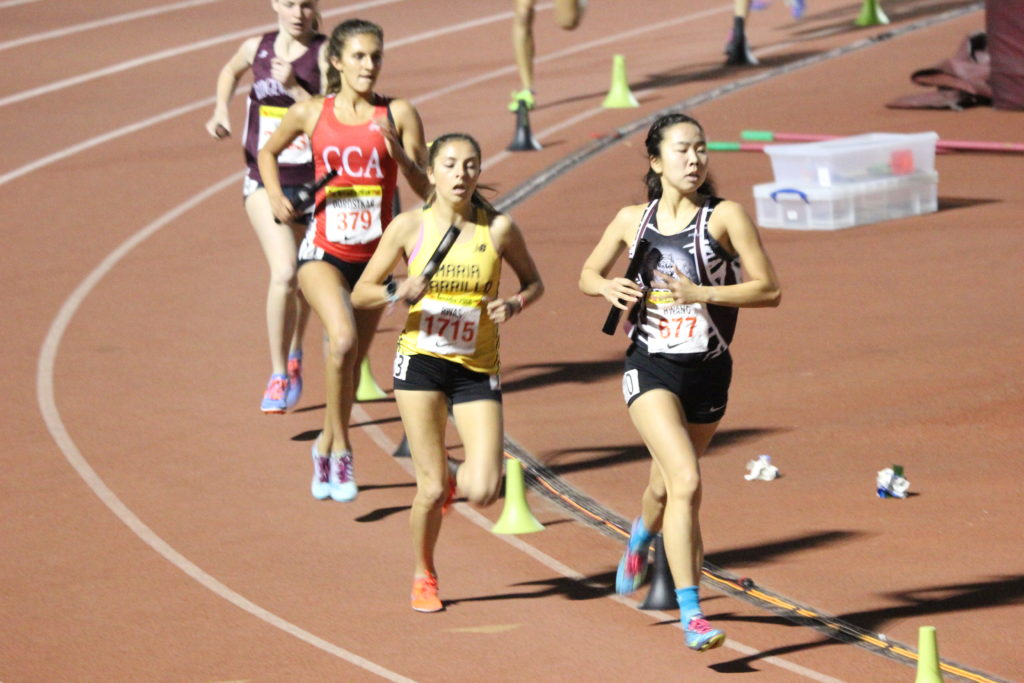 Athlete prepares for pole vault on a track with others watching.