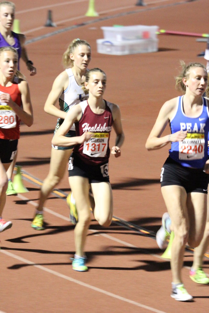 Athlete prepares for pole vault on a track with others watching.