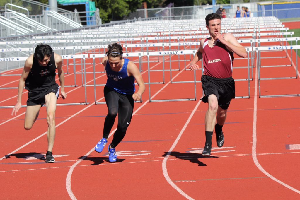 Athlete prepares for pole vault on a track with others watching.