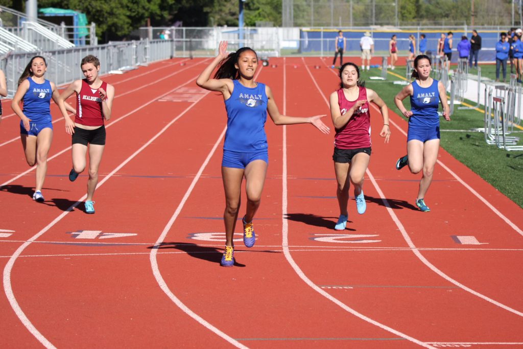 Athlete prepares for pole vault on a track with others watching.