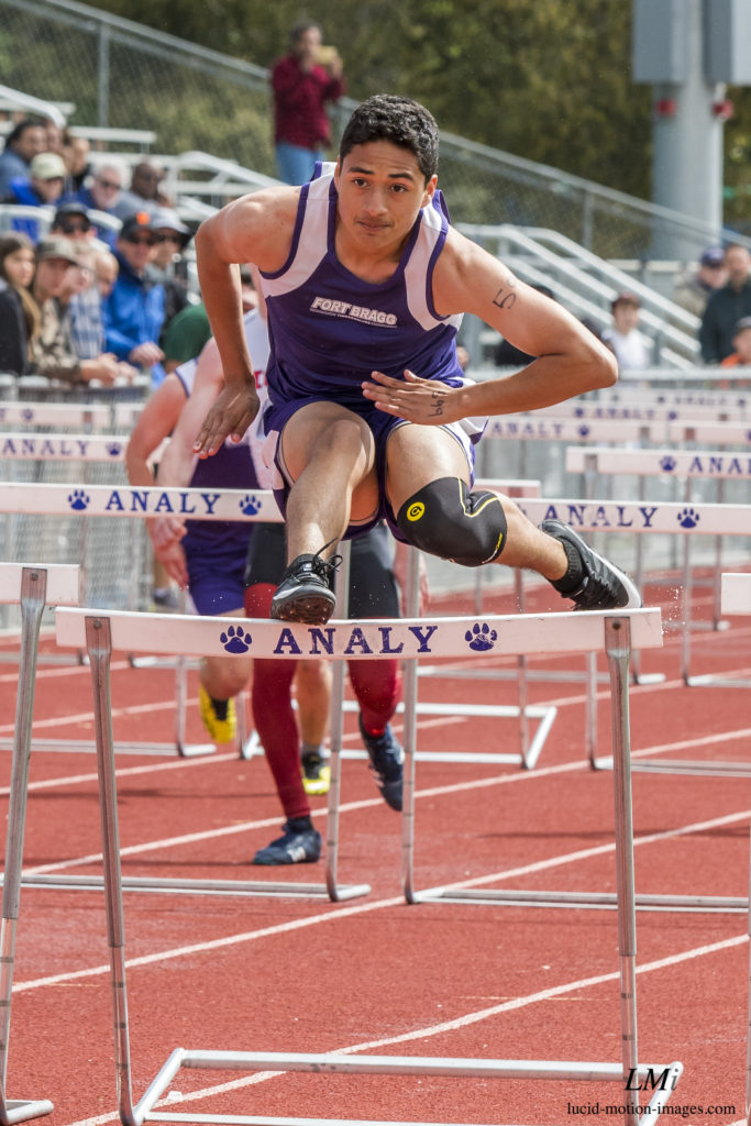 Athlete prepares for pole vault on a track with others watching.