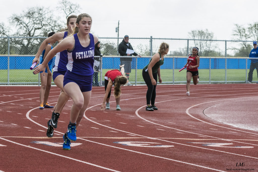 Athlete prepares for pole vault on a track with others watching.