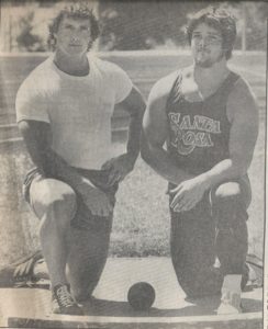Athlete prepares for pole vault on a track with others watching.
