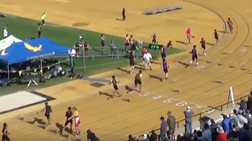 Athlete prepares for pole vault on a track with others watching.