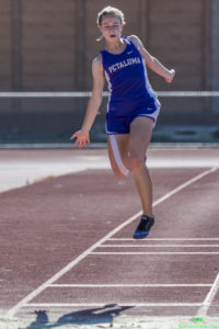 Athlete prepares for pole vault on a track with others watching.