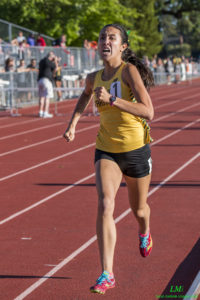 Athlete prepares for pole vault on a track with others watching.