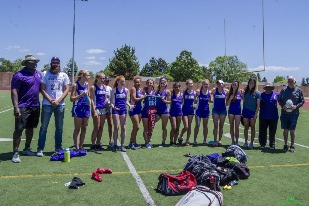Athlete prepares for pole vault on a track with others watching.