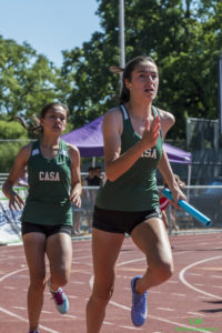 Athlete prepares for pole vault on a track with others watching.