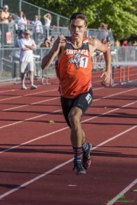 Athlete prepares for pole vault on a track with others watching.