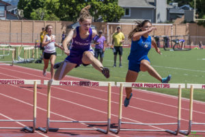 Athlete prepares for pole vault on a track with others watching.