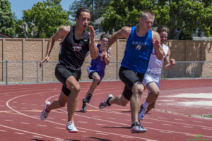 Athlete prepares for pole vault on a track with others watching.