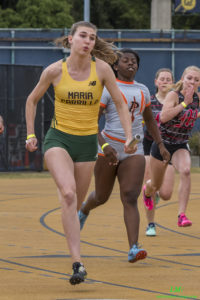 Athlete prepares for pole vault on a track with others watching.