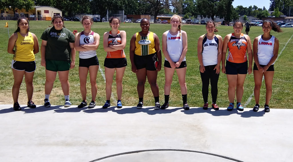 Athlete prepares for pole vault on a track with others watching.