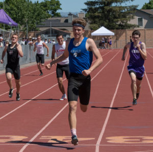 Athlete prepares for pole vault on a track with others watching.