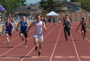 Athlete prepares for pole vault on a track with others watching.