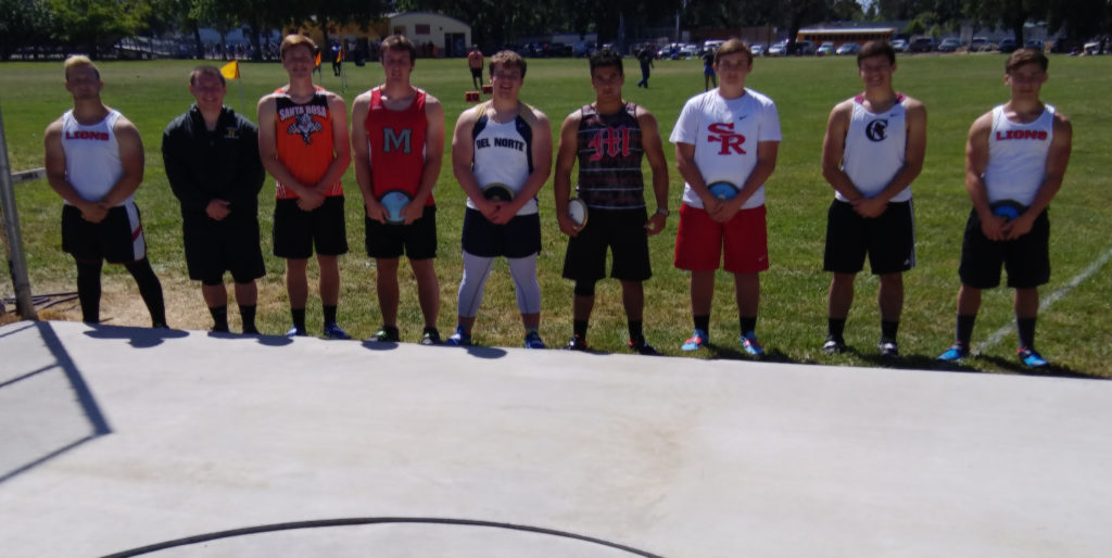 Athlete prepares for pole vault on a track with others watching.