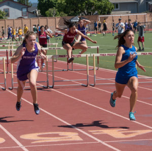 Athlete prepares for pole vault on a track with others watching.