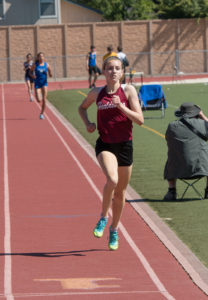 Athlete prepares for pole vault on a track with others watching.