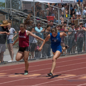 Athlete prepares for pole vault on a track with others watching.