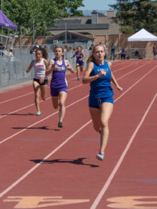Athlete prepares for pole vault on a track with others watching.