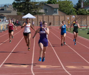 Athlete prepares for pole vault on a track with others watching.