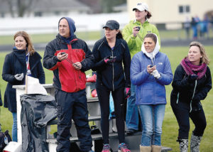 Athlete prepares for pole vault on a track with others watching.