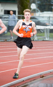 Athlete prepares for pole vault on a track with others watching.