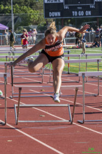 Athlete prepares for pole vault on a track with others watching.