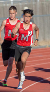 Athlete prepares for pole vault on a track with others watching.