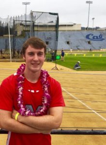 Athlete prepares for pole vault on a track with others watching.