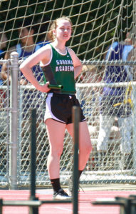 Athlete prepares for pole vault on a track with others watching.