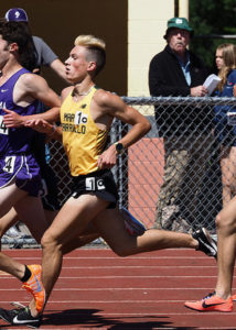 Athlete prepares for pole vault on a track with others watching.