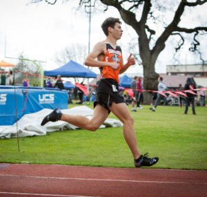 Athlete prepares for pole vault on a track with others watching.